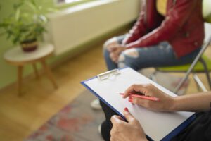Close up of a female psychologist taking notes and a students knees