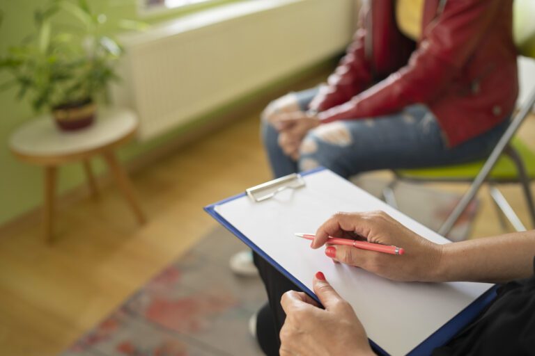 Close up of a female psychologist taking notes and a students knees