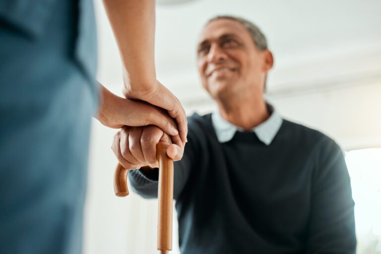 Cropped shot of a nurse helping an older man stand up and use his walking stick